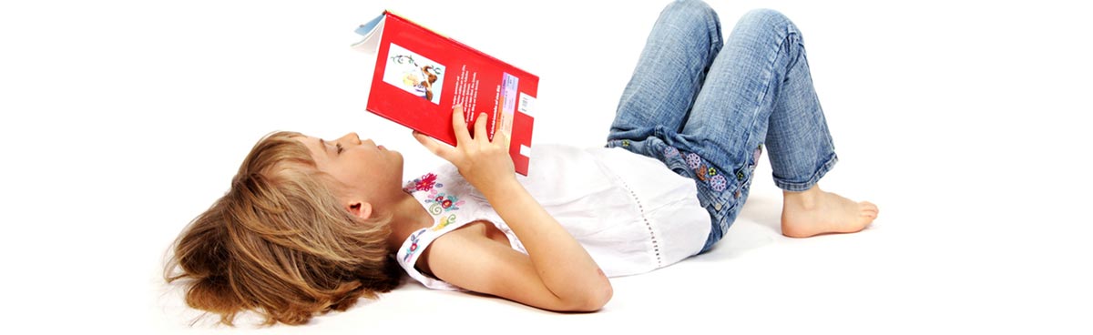 Kind liegt auf dem Rücken und liest ein Buch